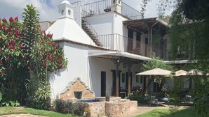 Un bâtiment blanc doté d’un balcon, d’une fontaine en pierre et d’une pelouse bien entretenue.