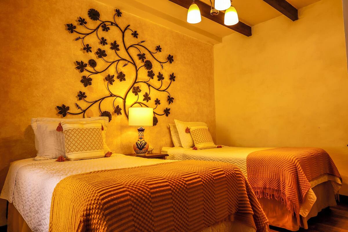 Habitación de hotel con dos camas, un adorno en la pared y una lámpara.