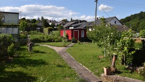 Un quartier résidentiel avec une maison rouge, un chemin pavé et de la verdure tout autour.