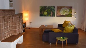 Un salon comprenant un canapé, une table basse, un banc et un téléviseur fixé au mur.