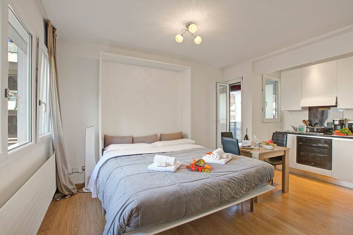 Une chambre d’hôtel moderne avec un grand lit, un petit bureau et une kitchenette.