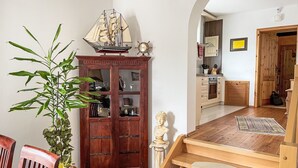 Een houten trap die naar een tweede verdieping leidt, een houten kast met glazen deuren, een potplant en een scheepsmodel op de bovenkant.