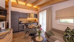 A modern living room with a sofa, coffee table, and a dining area with chairs and a table.