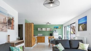 A modern living room with a black sofa, a dining area, and a kitchen with green walls. - Palet Breton by Interhome (Locquirec)