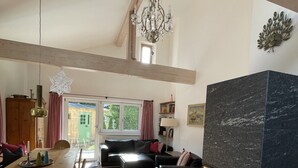 Amplia sala de estar con chimenea, mesa de comedor de madera y un gran ventanal.