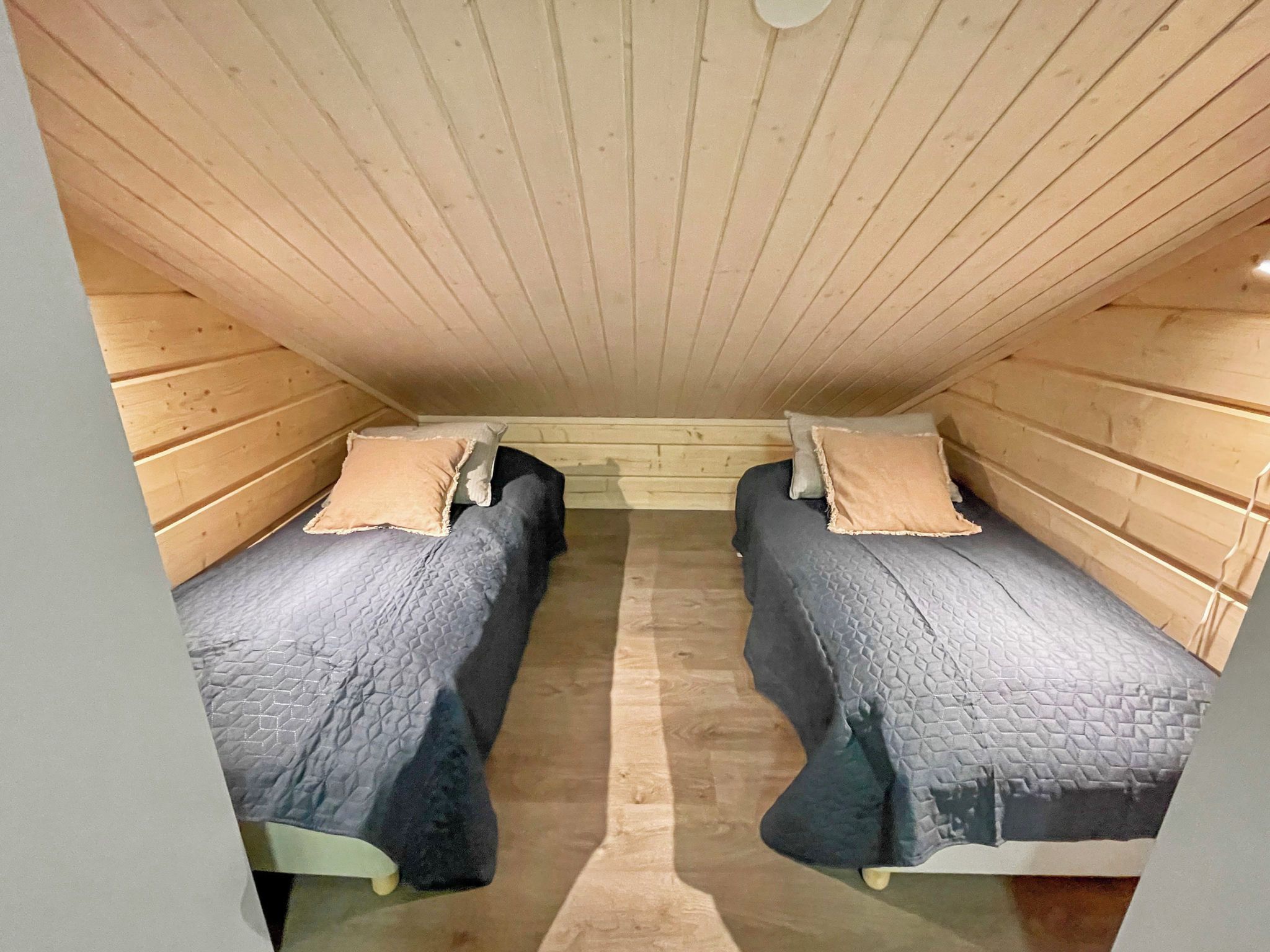 Ein kleiner, abgeschlossener Raum mit zwei Betten, jeweils mit Kissen und einer gesteppten Decke.