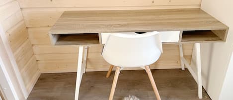 A wooden desk with a white chair, a fur rug on the floor, and a wooden wall.