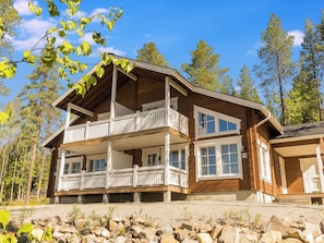 A two-story wooden cabin with a balcony, surrounded by trees. - South point apartments 4a by Interhome (Kittilä)