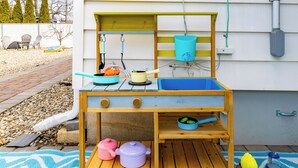Una cocina de juguete de madera con ollas, sartenes y un lavabo.