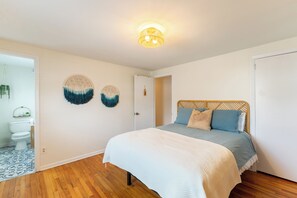 Ein Schlafzimmer mit einem Bett, Holzboden, einer weißen Tür und Wanddekoration.