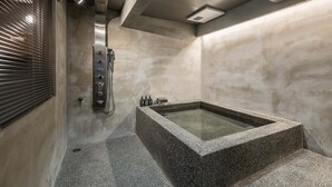 A modern bathroom with a freestanding bathtub, a showerhead, and a control panel. - Sansuikyo Machiya House (Kanazawa)