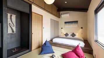 A modern bedroom with a bed, pillows, a tatami mat, a hanging light fixture, and a painting on the wall.