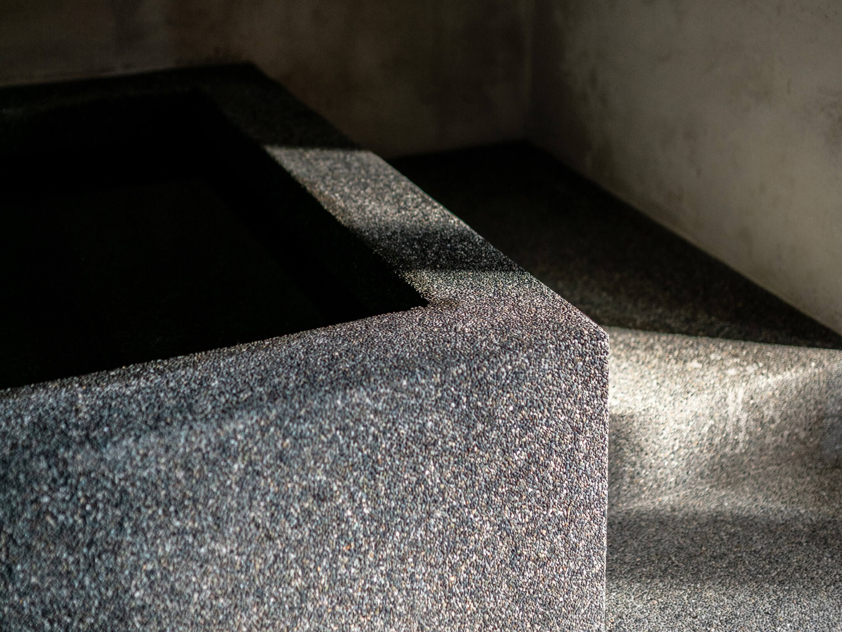 A close-up of a textured stone surface with a dark shadow cast on it.