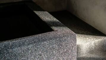 A close-up of a textured stone surface with a dark shadow cast on it.