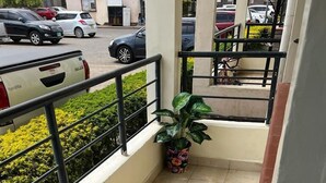 Een balkon met betegelde vloer, een plant in pot en een kleine tafel.