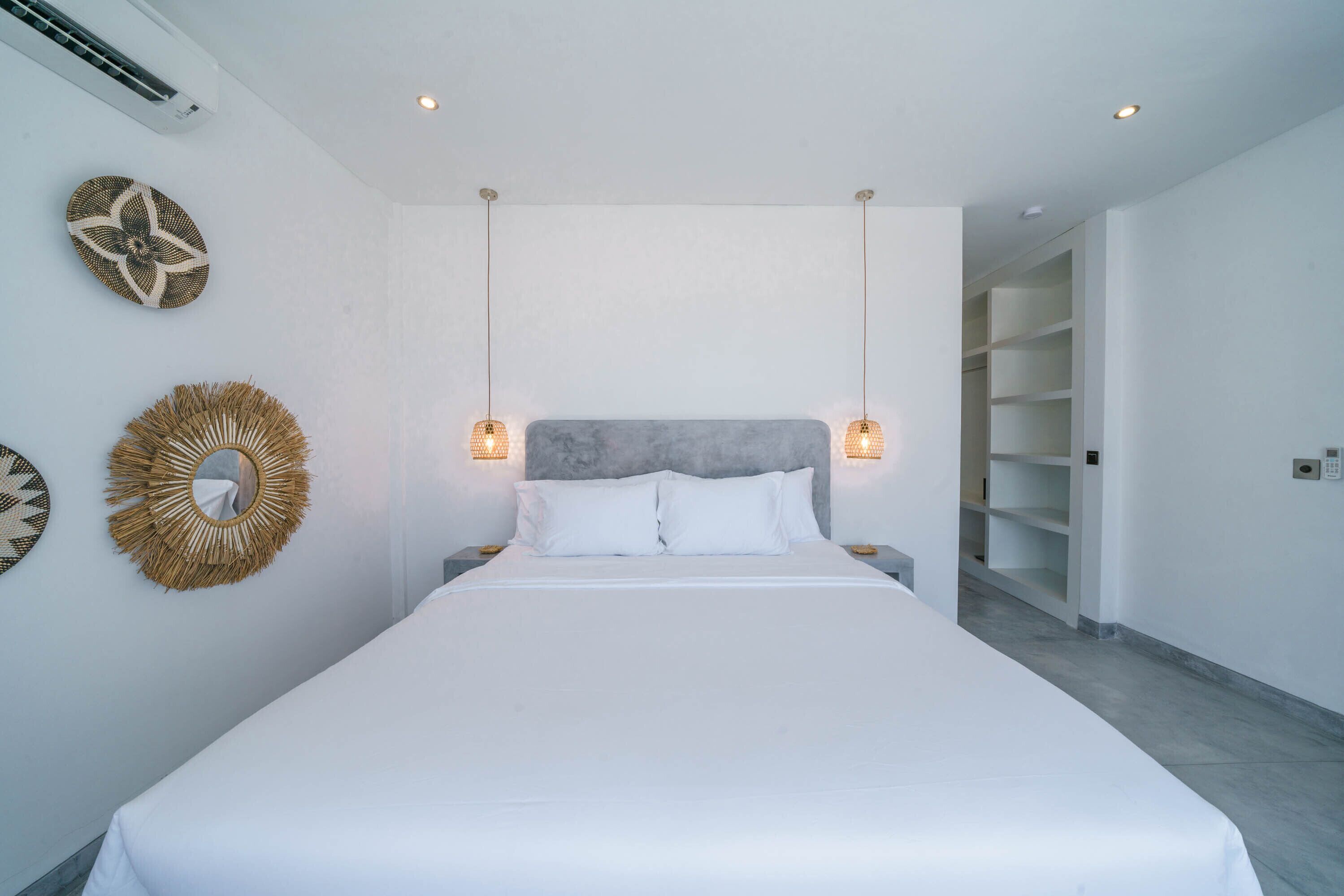 Une chambre moderne avec un grand lit, deux lampes fixées au mur et des œuvres d’art décoratives.