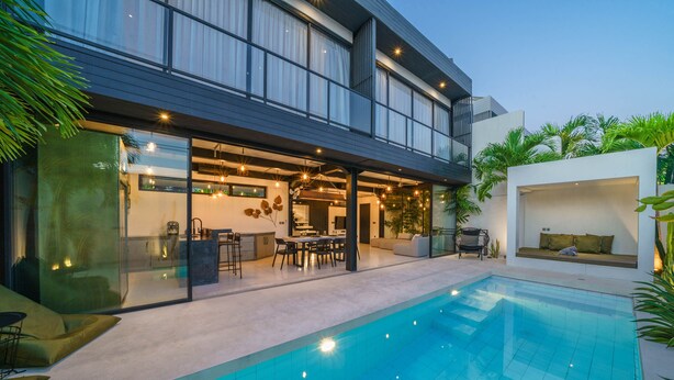 A modern house with a swimming pool, glass doors leading to a dining area, and a balcony with plants. - Villa Bali Townhouse (Kerobokan)
