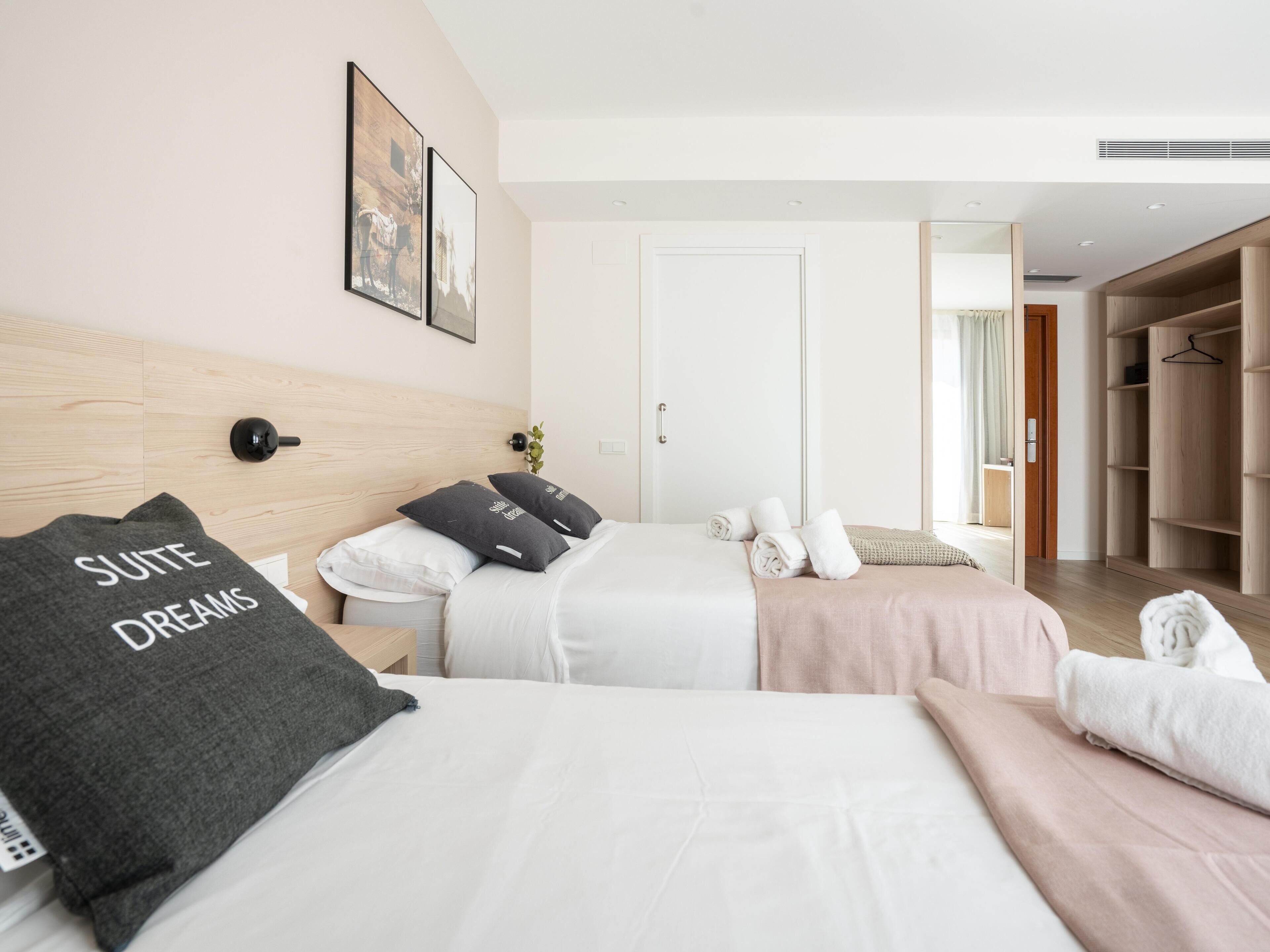 Une chambre d’hôtel avec deux lits, une armoire et une porte donnant sur une autre pièce.