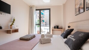 A modern hotel room with a large bed, a flat-screen TV, a small table with a coffee maker, and a window with a view of the city. - Limehome Barcelona Carrer de Besalú 82 (Barcelona)