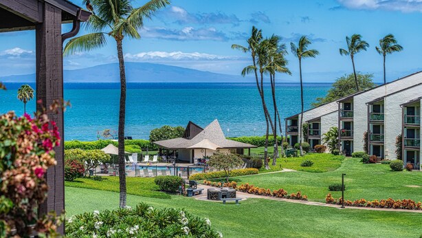 Un resort con piscina, palmeras y vista al océano.