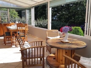 Relax in the serene patio area with a round table and comfortable chairs, surrounded by lush greenery views.