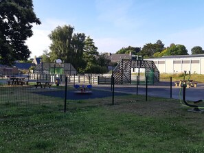 Relax and play in our outdoor recreational area, featuring a playground with a climbing frame and swings, picnic tables, and benches.