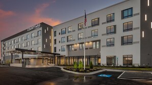A Courtyard by Marriott hotel with a modern design, featuring a covered entrance, multiple floors, and a flagpole. - Courtyard by Marriott Conway (Conway)