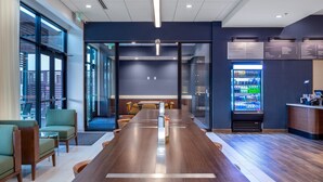 A modern conference room with a long wooden table, comfortable seating, a vending machine, and a view through large windows. - Courtyard by Marriott Conway (Conway)