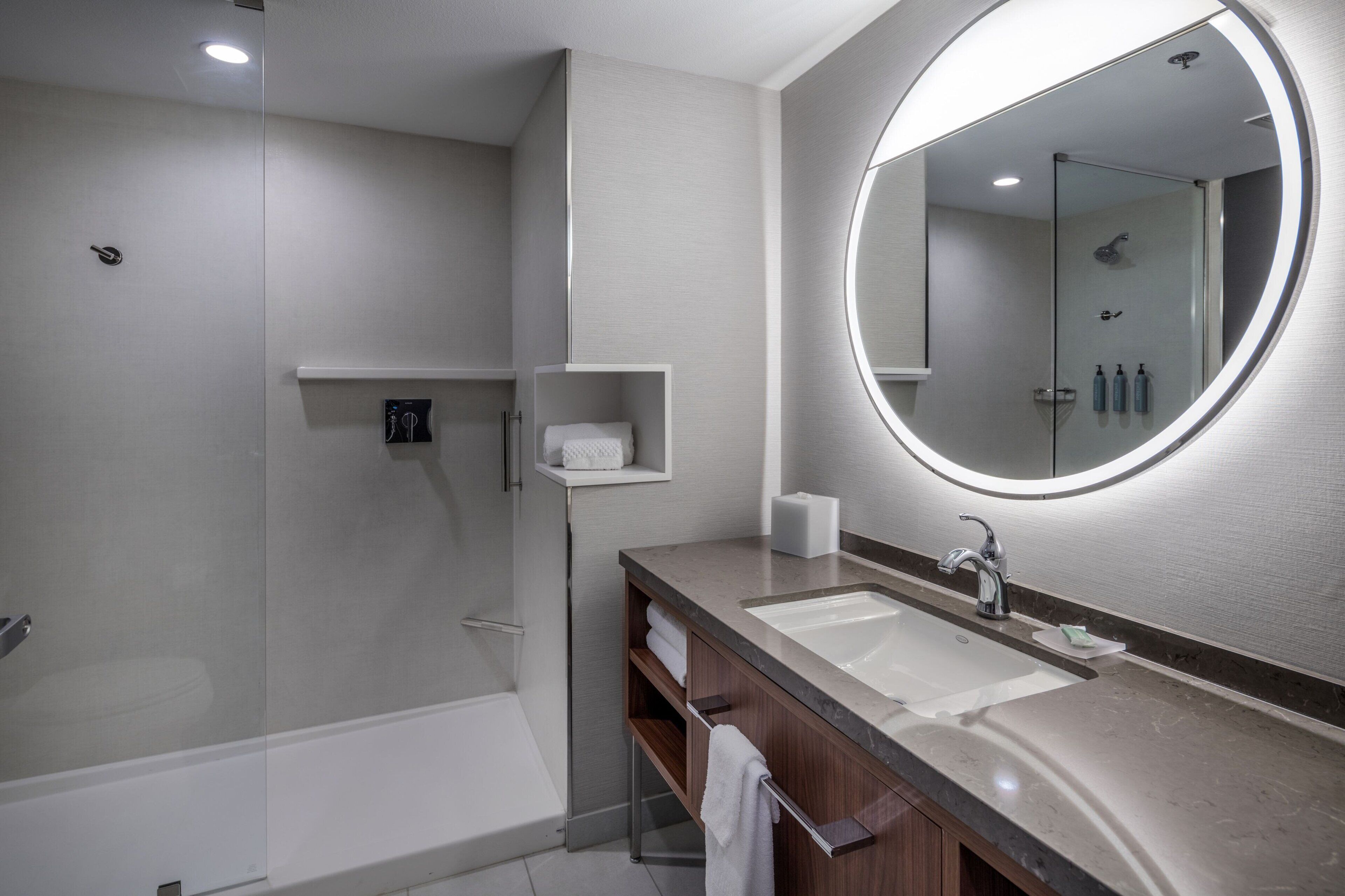 Un baño moderno con cabina de ducha de vidrio, un espejo grande y un mueble de tocador doble.