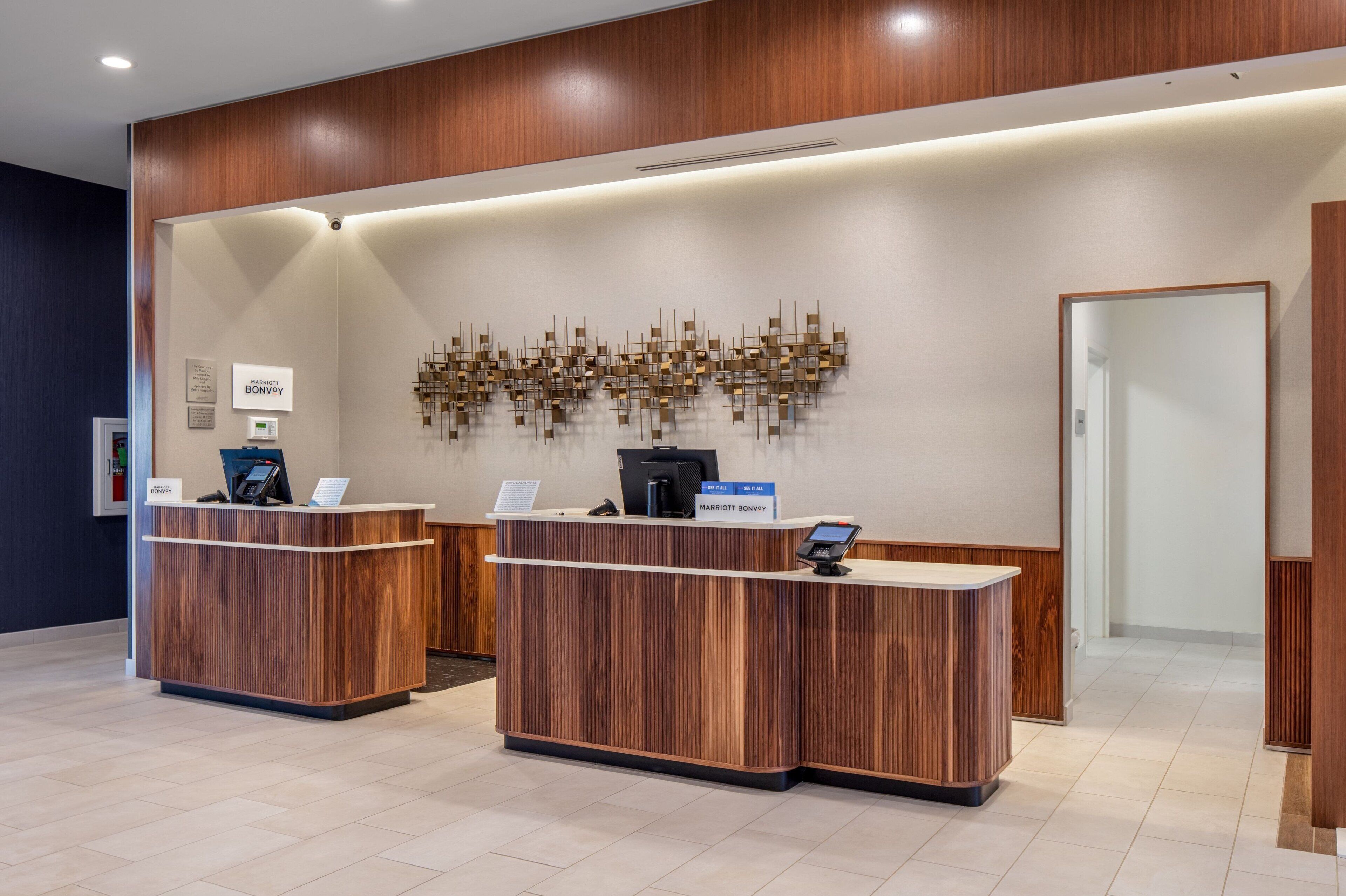 A reception desk with a wooden finish, a wall-mounted art piece, and a sign indicating the location as 'Marriott Bonvoy'.