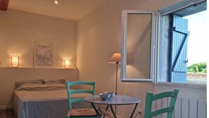 Ein Schlafzimmer mit einem Bett, zwei Stühlen, einem Tisch und einem Fenster mit Fensterläden.