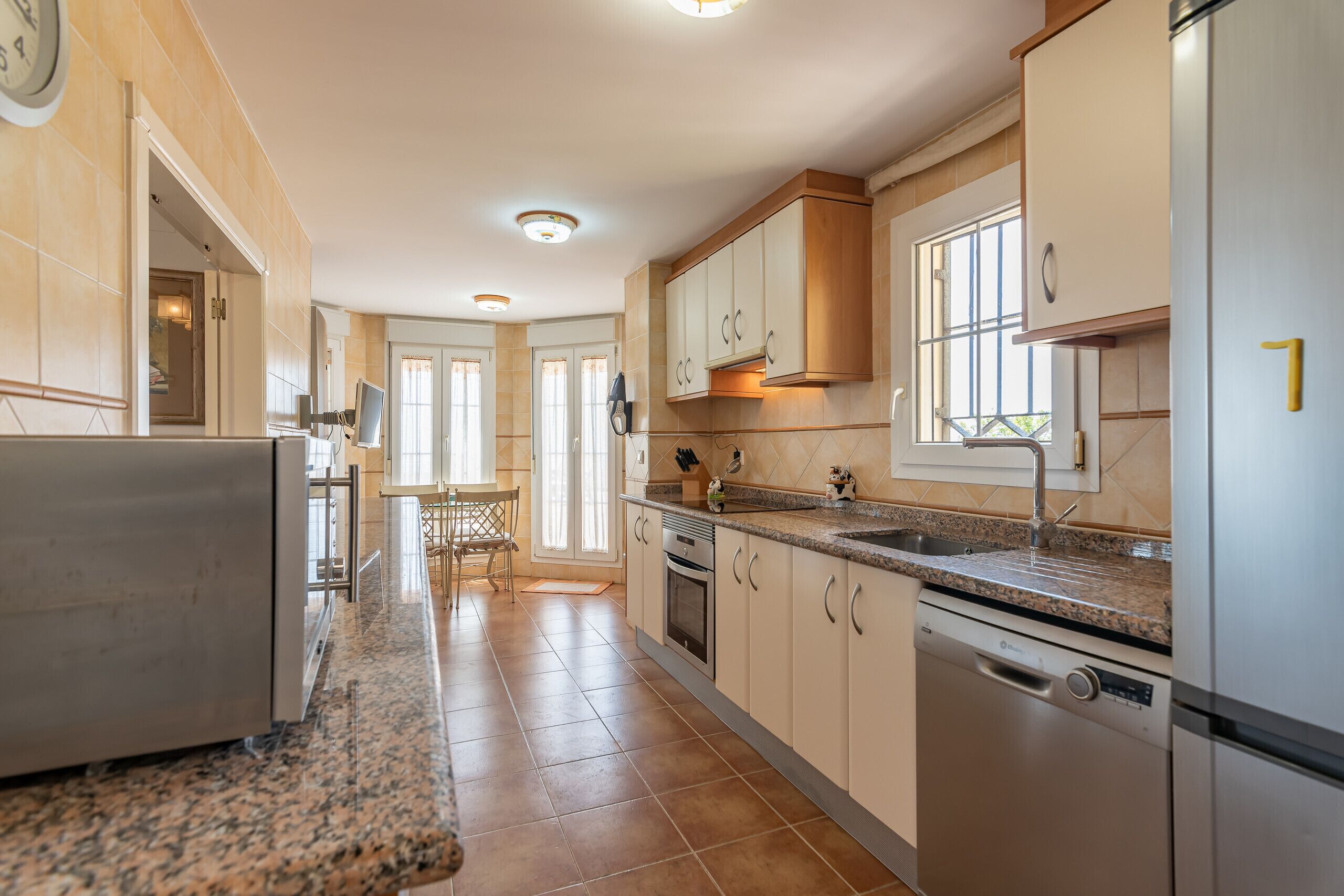 A modern kitchen with granite countertops, stainless steel appliances, and light wood cabinetry.