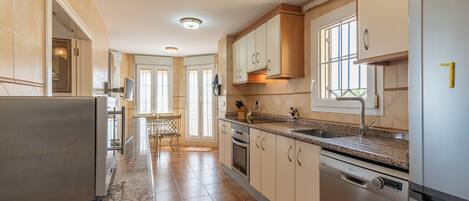 A modern kitchen with granite countertops, stainless steel appliances, and light wood cabinetry.