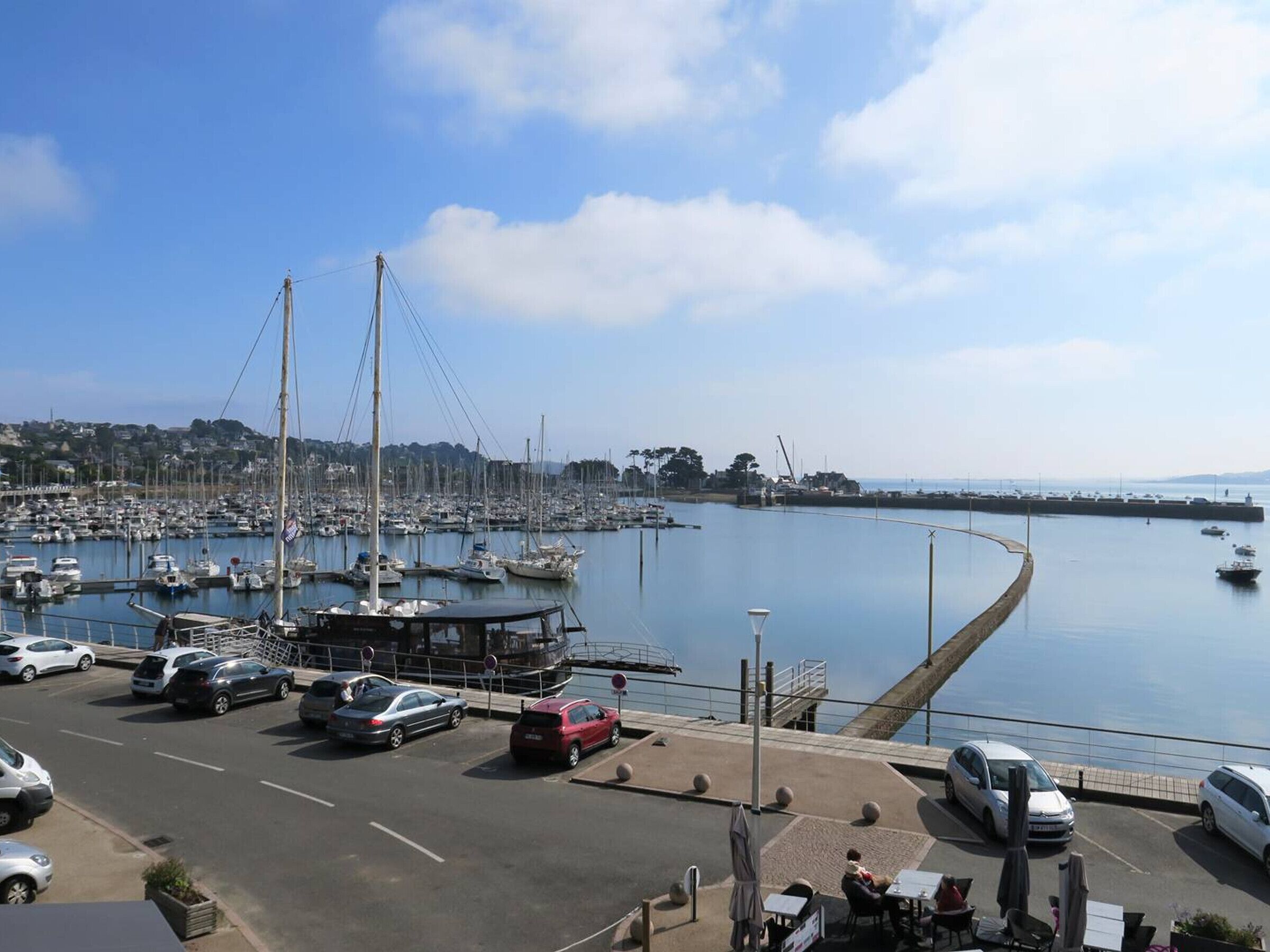 Un port de plaisance avec des bateaux, un espace de stationnement et une vue sur la côte.