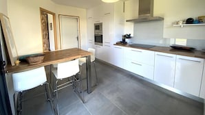 Una cocina moderna con armarios blancos, encimera de madera y lámpara colgante.