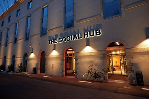 A building with 'The Social Hub' sign, arched doorways, and a bicycle parked outside.