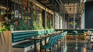 Un restaurant doté d’un long comptoir, de banquettes recouvertes d’un tissu vert et d’une rangée de tables avec des chaises.