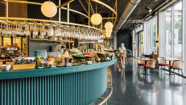 Un espace bar doté d’un comptoir de couleur turquoise, de verres suspendus et d’une variété de plats et de boissons.