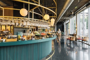 Zona de bar con mostrador turquesa, copas colgantes y diferentes alimentos y bebidas.