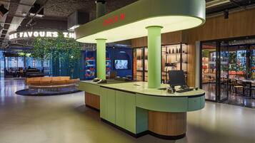 A reception desk with a 'CHECK IN' sign, a seating area with a sofa, and a view of the interior space.