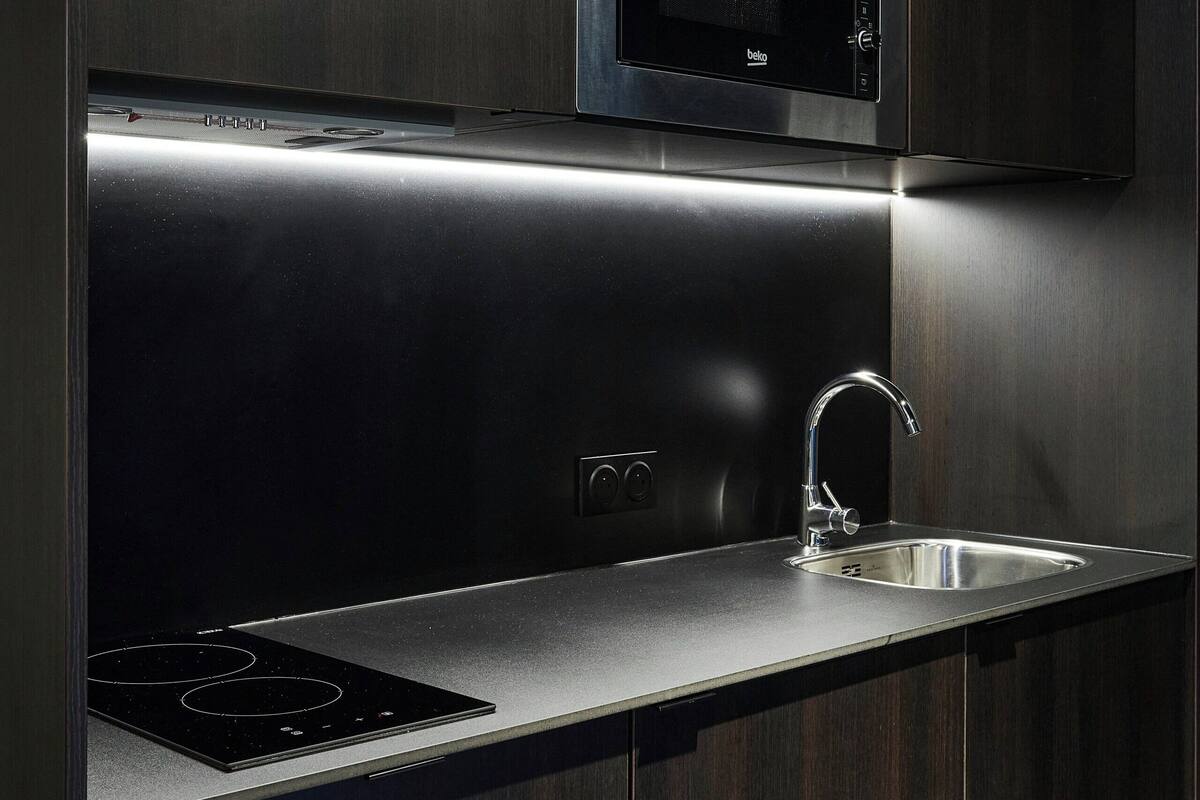 Een moderne keuken met een ingebouwde magnetron, een roestvrijstalen spoelbak en een gasfornuis.