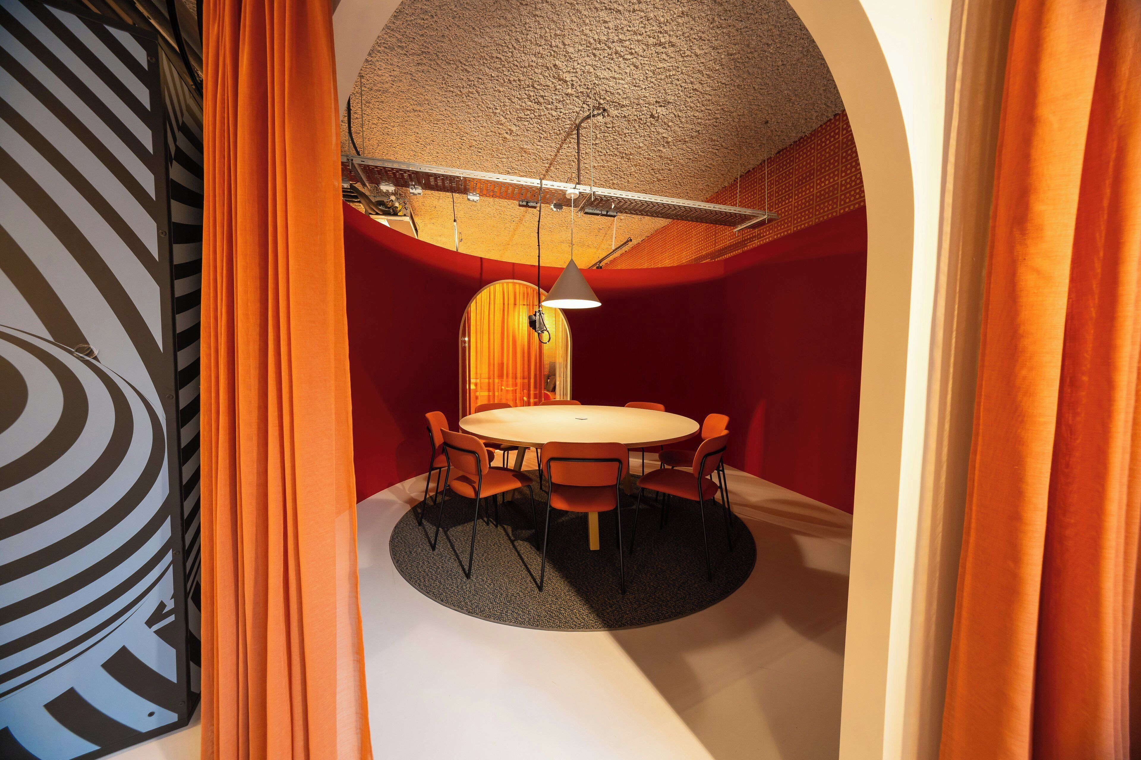 A conference room with a round table, six chairs, and a ceiling light fixture.