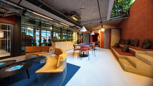 Un intérieur moderne avec des coins salon, des tables et une vue sur l’extérieur.