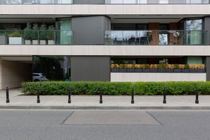 A modern multi-story building with balconies, large windows, and a well-maintained garden area.