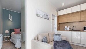 Un appartement moderne comprenant un coin cuisine, un lit avec une tête de lit, un canapé et un espace repas.