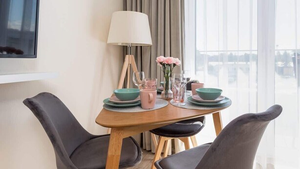 Un coin repas avec une table dressée pour quatre personnes, une lampe et une vue sur l’extérieur.