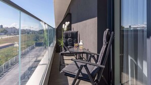 Un balcon avec deux chaises, une petite table et un pot de fleurs.