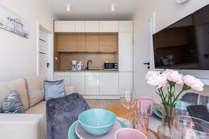 A modern living room with a sofa, coffee table, and a dining area with a table set for two.
