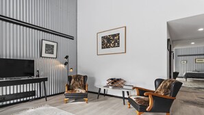A modern living room with a flat-screen TV, two armchairs, a coffee table, and a framed artwork on the wall. - The Cubby House by Wine Coast Holiday Rentals (WHITES VALLEY)