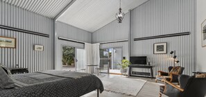 A spacious bedroom with a large bed, a TV, and a seating area with a chair and a sofa. - The Cubby House by Wine Coast Holiday Rentals (WHITES VALLEY)